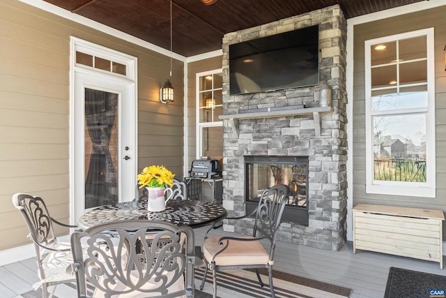 deck with outdoor dining space and a multi sided fireplace