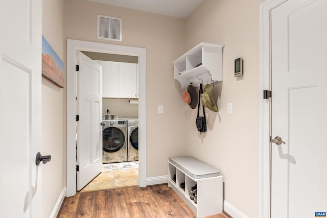 mudroom with baseboards, wood finished floors, visible vents, and washer and dryer