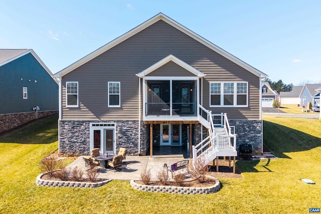 rear view of property featuring stone siding, a sunroom, a patio, and stairway