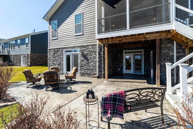 rear view of house with stone siding, a patio area, and french doors