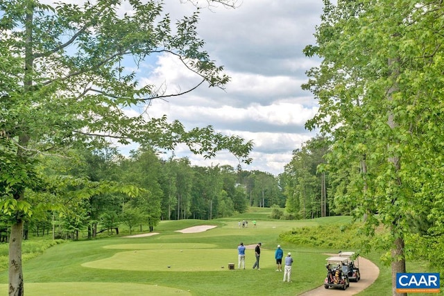 view of community featuring view of golf course and a yard