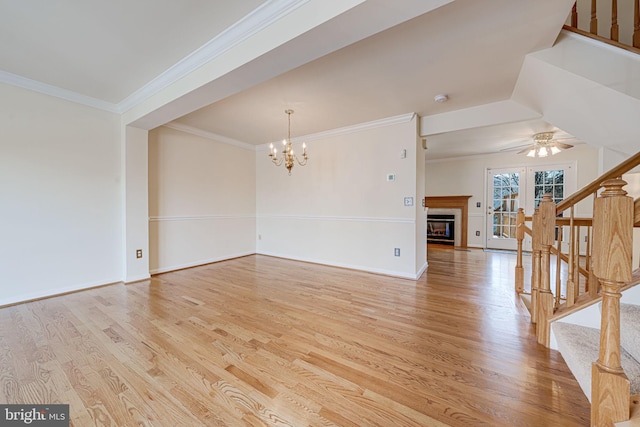 living room with ceiling fan with notable chandelier, baseboards, stairs, light wood-style floors, and a glass covered fireplace