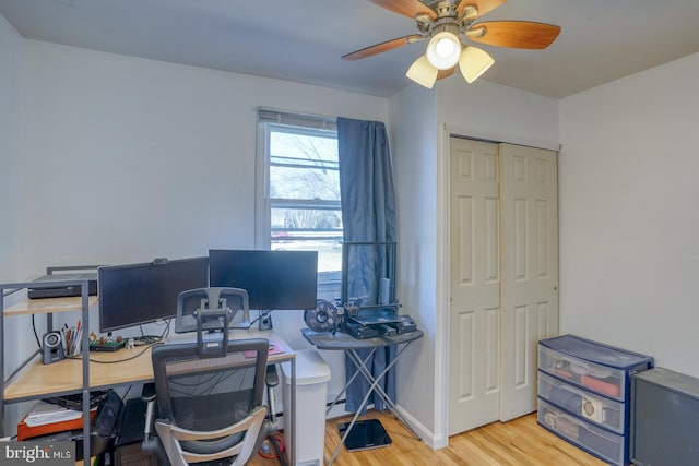 home office with light wood-style floors, ceiling fan, and baseboards