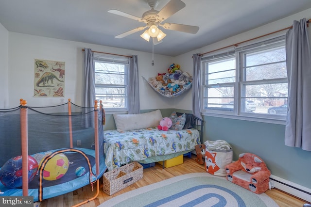 bedroom featuring ceiling fan, baseboard heating, and wood finished floors