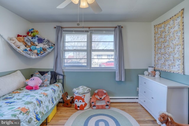 bedroom with a ceiling fan, light wood-type flooring, and baseboard heating