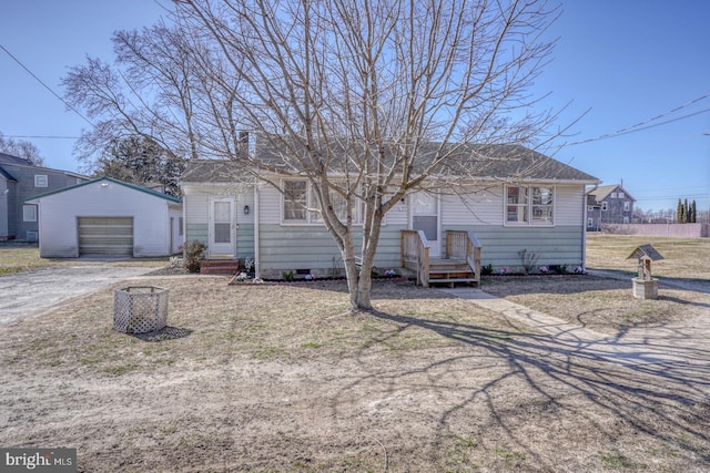 ranch-style house featuring an outbuilding, a detached garage, dirt driveway, a shingled roof, and crawl space