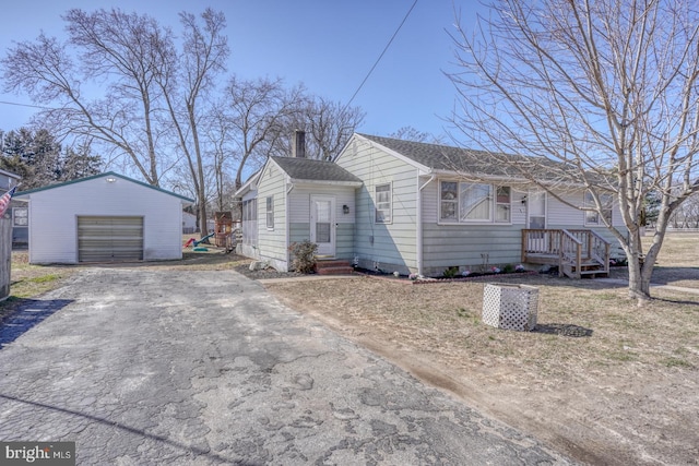 view of front of house with aphalt driveway, roof with shingles, an outdoor structure, and a detached garage