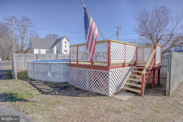 rear view of property with fence, a deck, and a fenced in pool