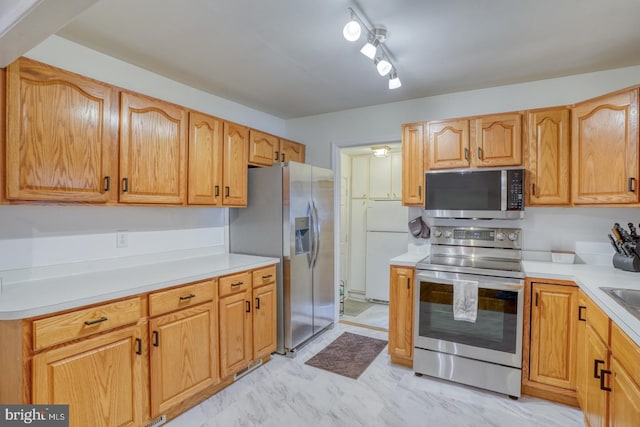 kitchen with appliances with stainless steel finishes, marble finish floor, light countertops, and a sink