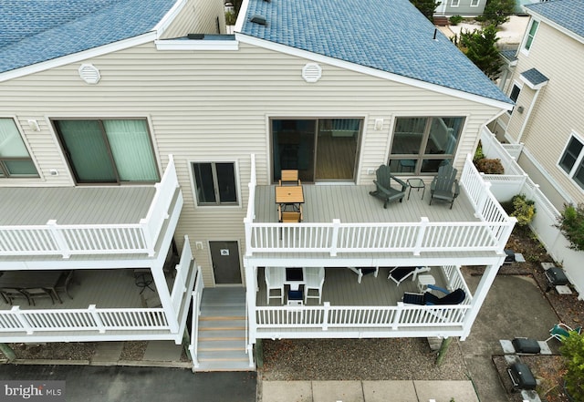 view of front of house with a shingled roof, a porch, and fence