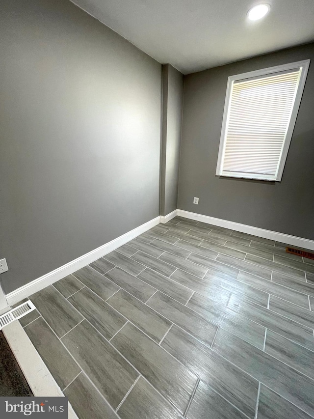 spare room featuring visible vents, baseboards, and wood finish floors