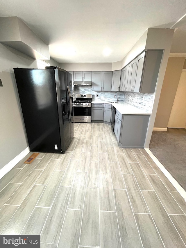 kitchen with dishwasher, stainless steel gas range, gray cabinets, refrigerator with ice dispenser, and a sink