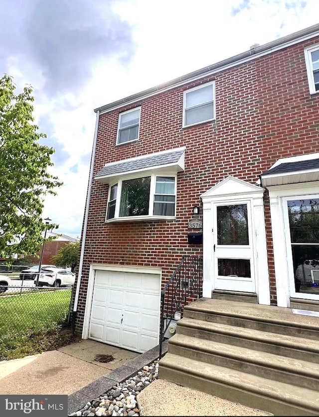 view of front of property featuring entry steps, brick siding, an attached garage, and fence