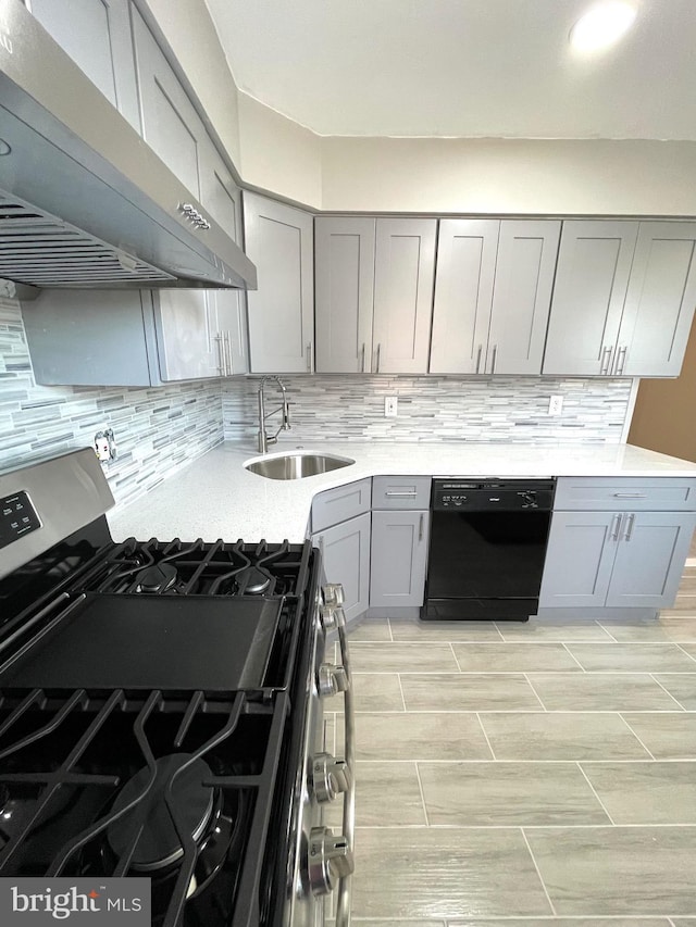 kitchen featuring gray cabinets, a sink, stainless steel gas range, dishwasher, and under cabinet range hood