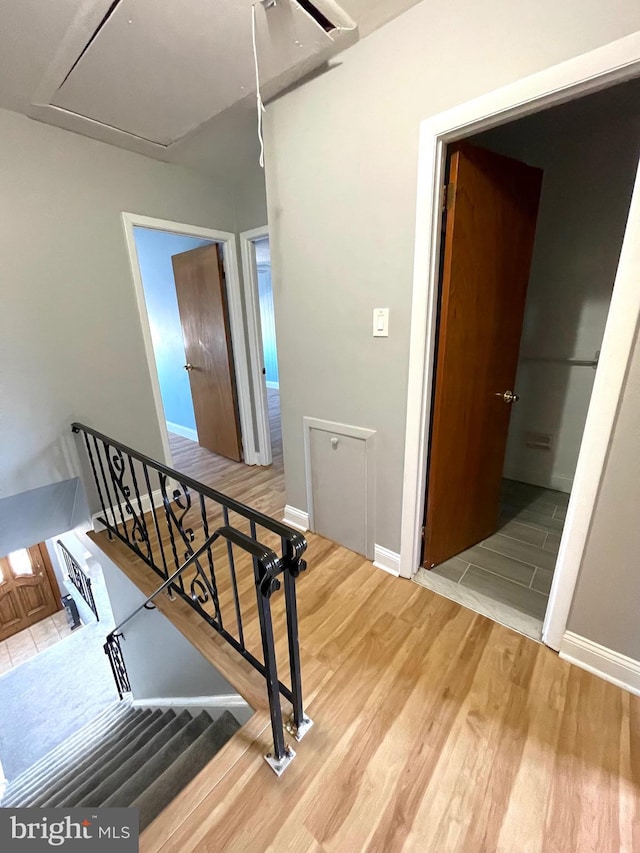 hallway featuring an upstairs landing, wood finished floors, and attic access