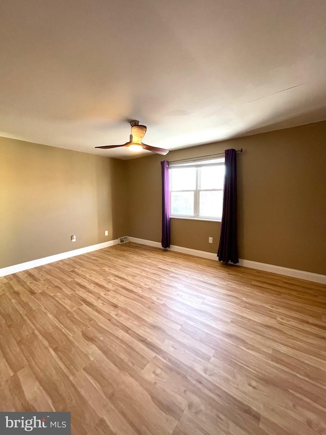 unfurnished room featuring light wood-type flooring, visible vents, ceiling fan, and baseboards