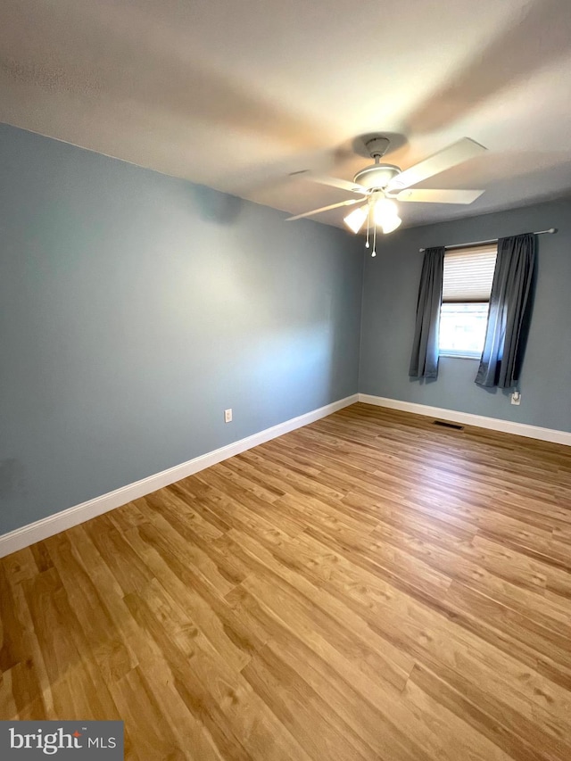 empty room featuring light wood-style flooring, visible vents, baseboards, and ceiling fan