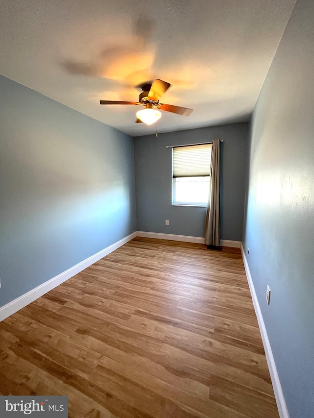 unfurnished room with ceiling fan, wood finished floors, and baseboards