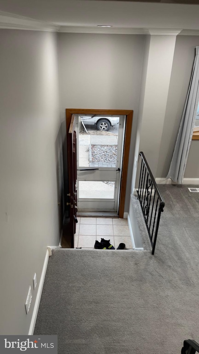 staircase with baseboards, visible vents, ornamental molding, tile patterned floors, and carpet flooring