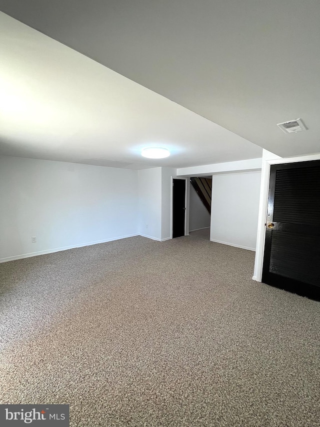 finished below grade area featuring baseboards, visible vents, and carpet flooring