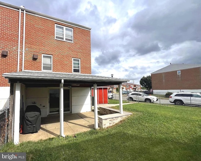 back of house featuring brick siding, a lawn, a patio area, and fence