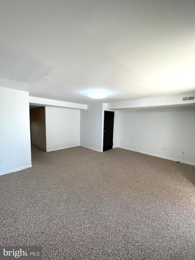 finished below grade area featuring baseboards, visible vents, and carpet flooring