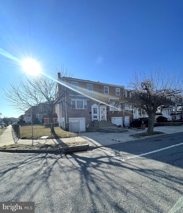 view of front of house featuring concrete driveway, an attached garage, and fence