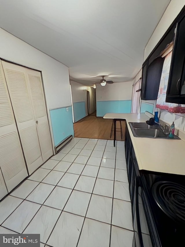 kitchen with light tile patterned flooring, a sink, a ceiling fan, light countertops, and dark cabinetry