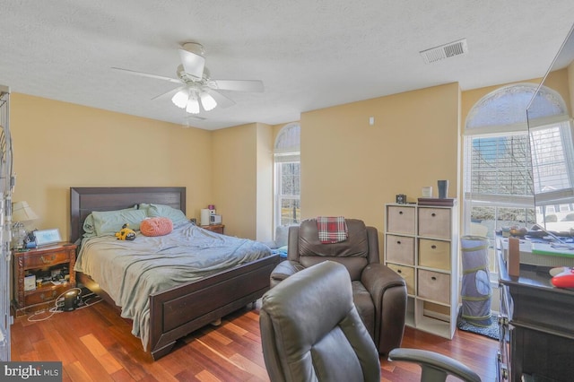 bedroom featuring a textured ceiling, wood finished floors, visible vents, and a ceiling fan