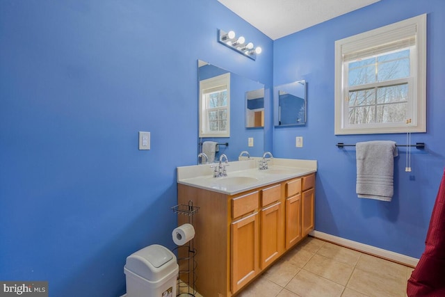 full bath with tile patterned flooring, a sink, baseboards, and double vanity