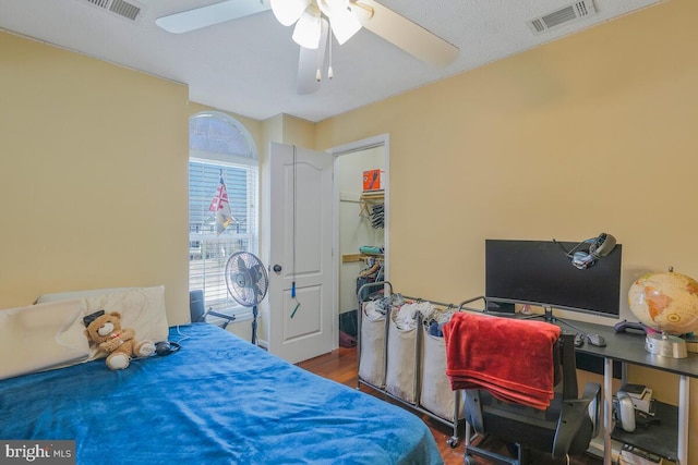 bedroom with ceiling fan, a closet, wood finished floors, and visible vents