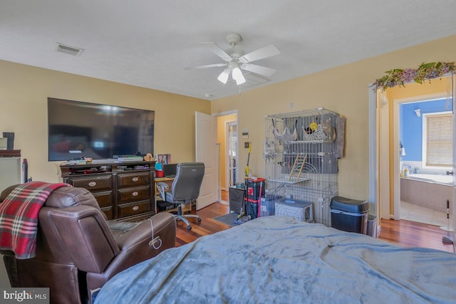 bedroom featuring ensuite bath, visible vents, ceiling fan, and wood finished floors