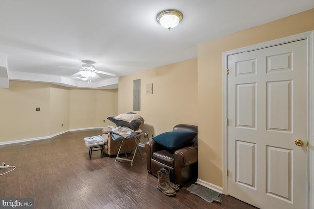 sitting room featuring a ceiling fan, electric panel, baseboards, and wood finished floors