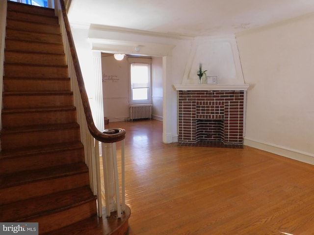 interior space featuring baseboards, a tiled fireplace, radiator heating unit, and wood finished floors