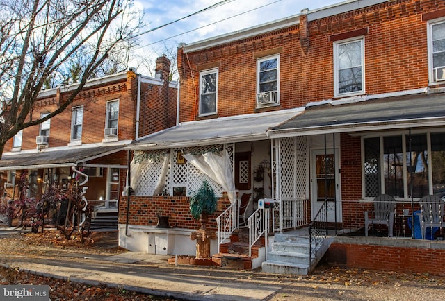 townhome / multi-family property with covered porch, cooling unit, and brick siding