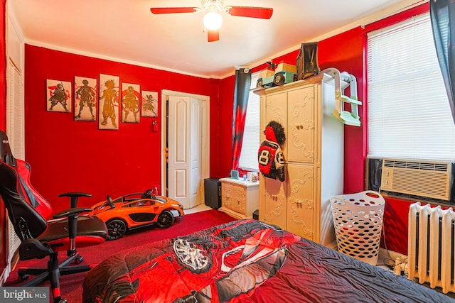 carpeted bedroom with cooling unit, multiple windows, ceiling fan, and radiator heating unit