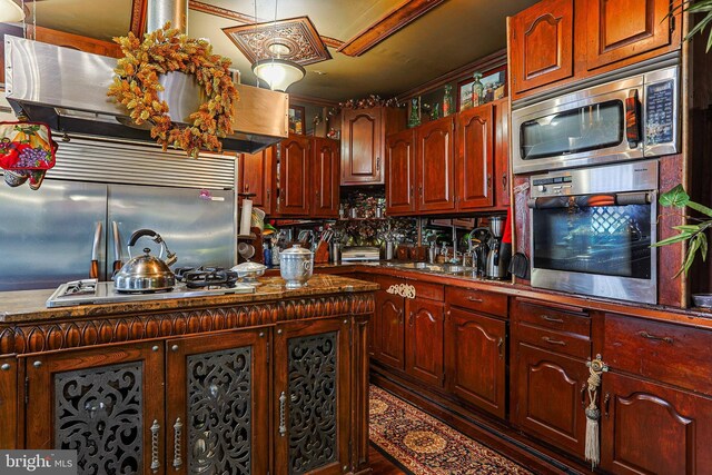 kitchen featuring reddish brown cabinets, stainless steel appliances, dark countertops, and decorative backsplash