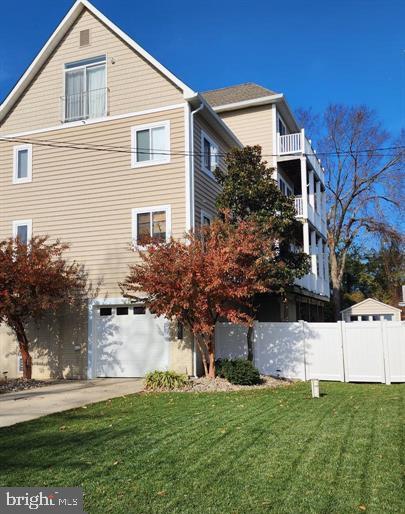 view of side of home featuring a garage, a yard, concrete driveway, and fence