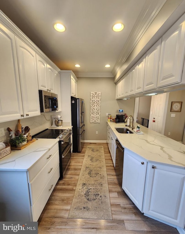 kitchen featuring stainless steel appliances, white cabinetry, light wood-style floors, and a peninsula