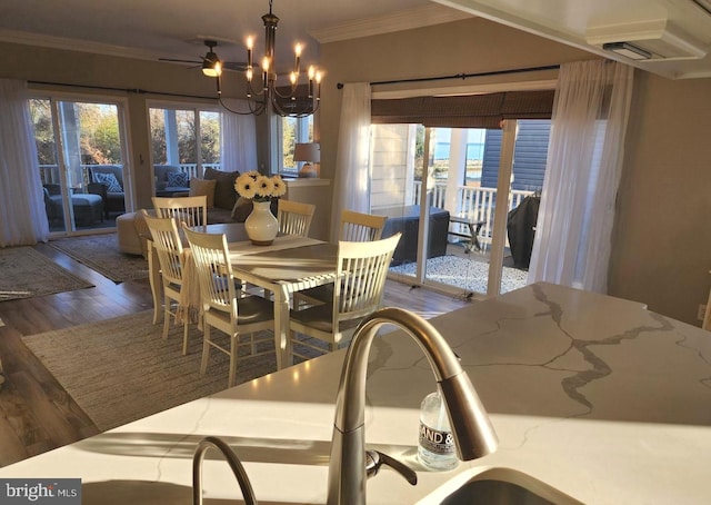 dining room with a healthy amount of sunlight, crown molding, an inviting chandelier, and wood finished floors