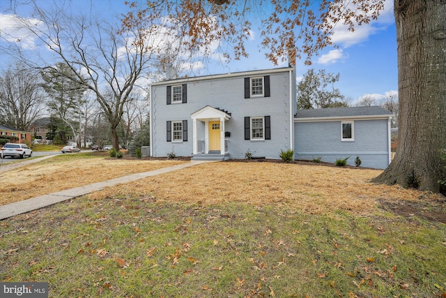 colonial home with a front lawn and brick siding