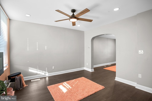 spare room featuring arched walkways, recessed lighting, baseboards, and wood finished floors