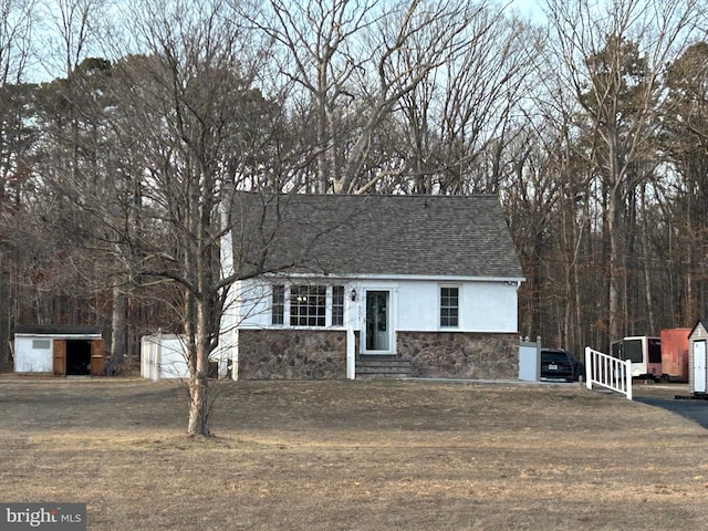 view of front of property featuring stucco siding, a shingled roof, entry steps, stone siding, and an outdoor structure