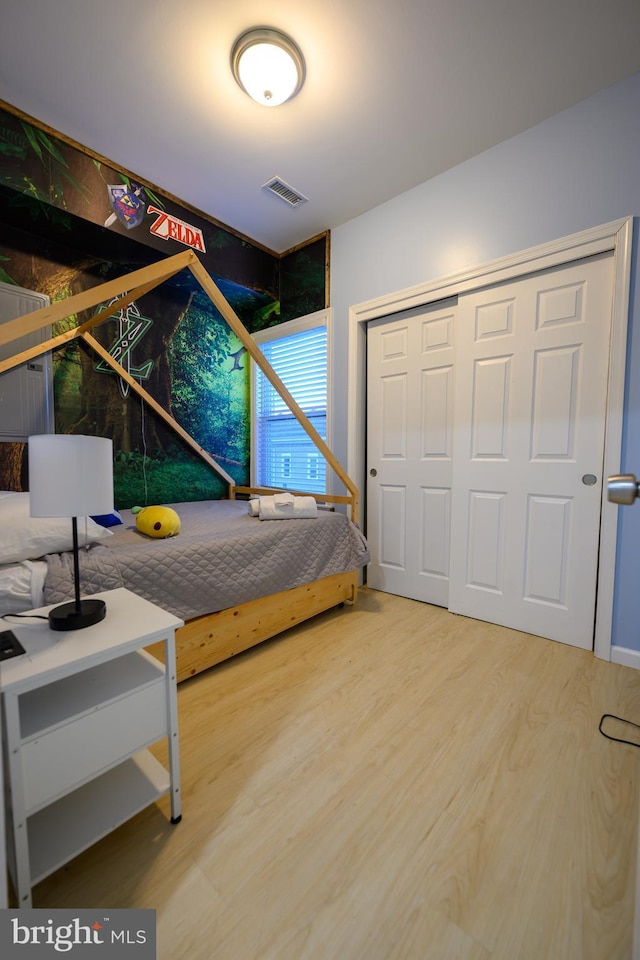 bedroom with a closet, visible vents, and wood finished floors