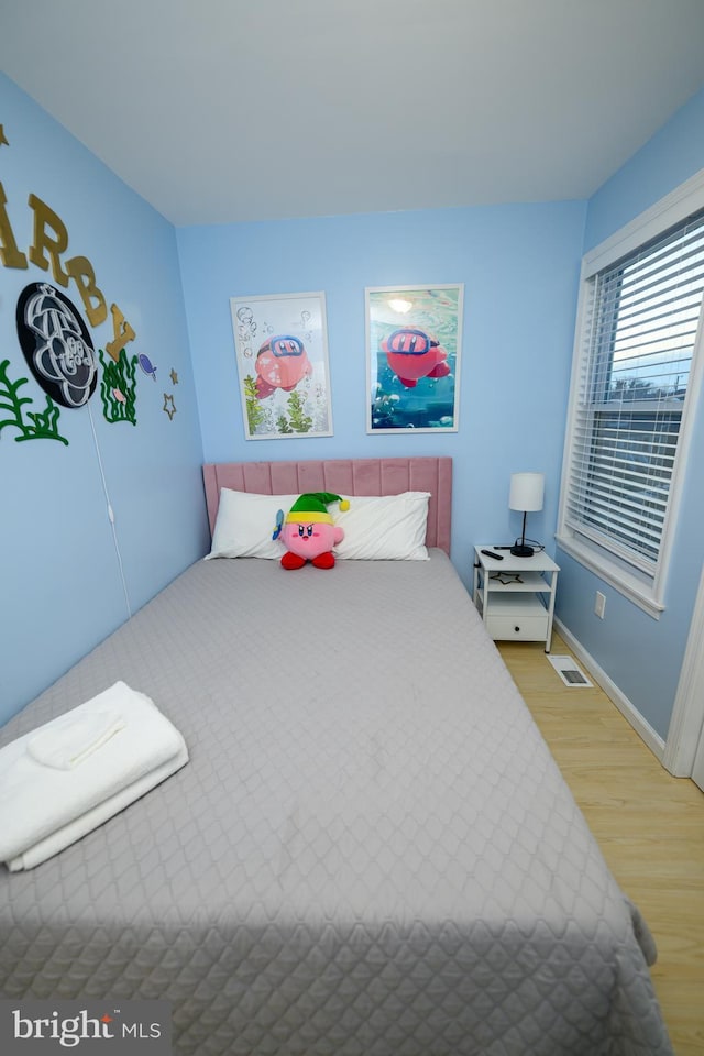 bedroom with visible vents, light wood-style flooring, and baseboards