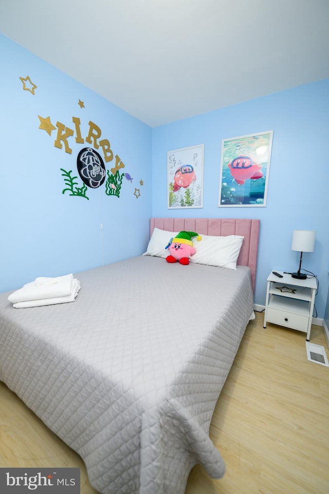 bedroom featuring wood finished floors, visible vents, and baseboards