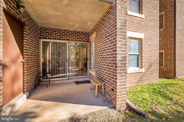 doorway to property with brick siding and a patio area