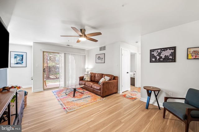 living area featuring visible vents, baseboards, ceiling fan, and light wood finished floors