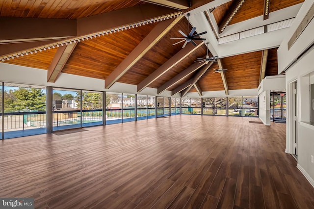 unfurnished living room featuring beamed ceiling, wooden ceiling, a ceiling fan, and wood finished floors