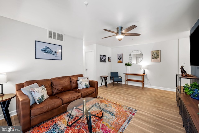 living area with visible vents, baseboards, light wood-style floors, and a ceiling fan